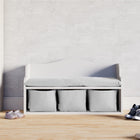 Die KraftKids Kindersitzbank weiß mit Sitzauflage steht auf hellem Holzfußboden und hat drei Stoffboxen zur Aufbewahrung. Daneben liegen pinke und schwarze Sneakers, links ist ein Kleiderschrank zu sehen. Perfekt als Kinderzimmer Möbel.