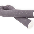 Die KraftKids GmbH Wickeltischrolle Musselin goldene Punkte auf Grau ist eine lange, biegsame graue Wickeltischrolle mit weißen und goldenen Sprenkeln und weißen Enden, die in einer losen Spirale auf weißem Hintergrund aufgewickelt ist.