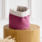 Ein magentafarbenes, dunkles, rundes Leinen-Körbchen von KraftKids sitzt auf einem runden Holztisch mit weißer Wandverkleidung und getrockneten Blättern - ideal als Aufbewahrungs-Wickeltisch und zur stilvollen Aufbewahrung von Essentials.