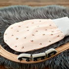 Ein weicher, rosafarbener KraftKids Strampelsack Frühling Sommer Musselin Kirschen mit Kirschenmuster ruht auf einem grauen Fellteppich neben einer hölzernen Spielzeugeisenbahn und geschwungenen Schienen auf einer Holzfläche.