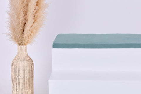Eine Vase mit getrocknetem Gras steht neben der KraftKids GmbH Sitzauflage für Ikea STUVA/SMÅSTAD Musselin nilblau und sorgt für Komfort und Stil.