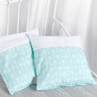 Zwei KraftKids Kissenbezug weiße Pfeile auf Mint dekorative Kissen mit weißen Pfeilmustern ruhen auf einer hellgrauen strukturierten Decke, vor einem weißen Metallbettgestell und weißen Vorhängen im Hintergrund.