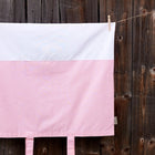 Der KraftKids Bezug für Wickeltischauflage mit weißen Punkten auf koralrosa bringt Stil in jeden Raum. Waschbar und charmant hängt der Bezug aus 100% Baumwolle dekorativ vor rustikalem Holzzaun an einer Wäscheleine.