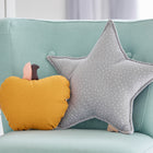 Ein hellblauer Sessel mit einem gelben Kürbiskissen und dem KraftKids Sternkissen Musselin grau Punkte mit weißen Tupfen verleiht jedem Kinderzimmer Charme und steht neben einer weißen Kommode.