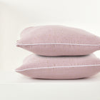 Zwei hellrosa "Kissenbezug Musselin goldene Punkte auf Rosa" von KraftKids mit kleinen goldenen Punkten sind auf einer weißen Fläche vor einem unifarbenen Hintergrund gestapelt - ideal, um jede Bettwäschekollektion mit elegantem Charme aufzuwerten.