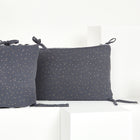 Zwei graue "Bettumrandung Nestchen Musselin goldene Punkte auf Grau" von KraftKids, handgefertigt aus 100% Baumwolle mit weißen und goldenen Punkten und gebundenen Ecken, sind auf weißen geometrischen Blöcken vor weißem Hintergrund abgebildet.