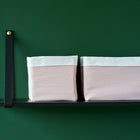 Zwei KraftKids Körbchen Doppelkrepp Rosa mit weißer Oberseite und hellrosafarbenen Seiten sitzen auf einem schwarzen Regal und bieten neben dem Wickeltisch vor einer dunkelgrünen Wand charmanten Stauraum - ideal, um das Nötigste zu organisieren.