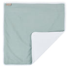 Die KraftKids Wickelunterlage Musselin mint ist eine hellgrüne, rechteckige Babydecke mit weißem Rand, einer umgeschlagenen Ecke, die die weiße, strukturierte Unterseite zeigt, und einem kleinen, hellbraunen Etikett, das in der oberen linken Ecke eingenäht ist.