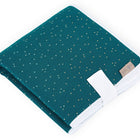 Die KraftKids Reisewickelunterlage Musselin goldene Punkte auf Petrol ist kompakt und stilvoll, mit goldenen Punkten, weißem Rand und tan Label - ideal als platzsparende Wickelauflage oder Reiseauflage für unterwegs.