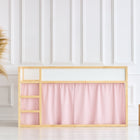 Ein minimalistisches Zimmer mit einem Bett mit Holzrahmen und KraftKids Hochbettvorhänge Set 2+1 Doppelkrepp Rosa für Kura Bett, einer geflochtenen Vase mit Pampasgras auf der linken Seite und zwei hölzernen Würfelhockern auf der rechten Seite vor einer weiß getäfelten Wand.