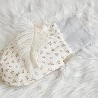 Ein KraftKids Strampelsack Herbst Winter Musselin Zweige braun mit einem grauen Bündchen ruht auf einer flauschigen weißen Oberfläche, die mit einer weichen weißen Feder verziert ist.